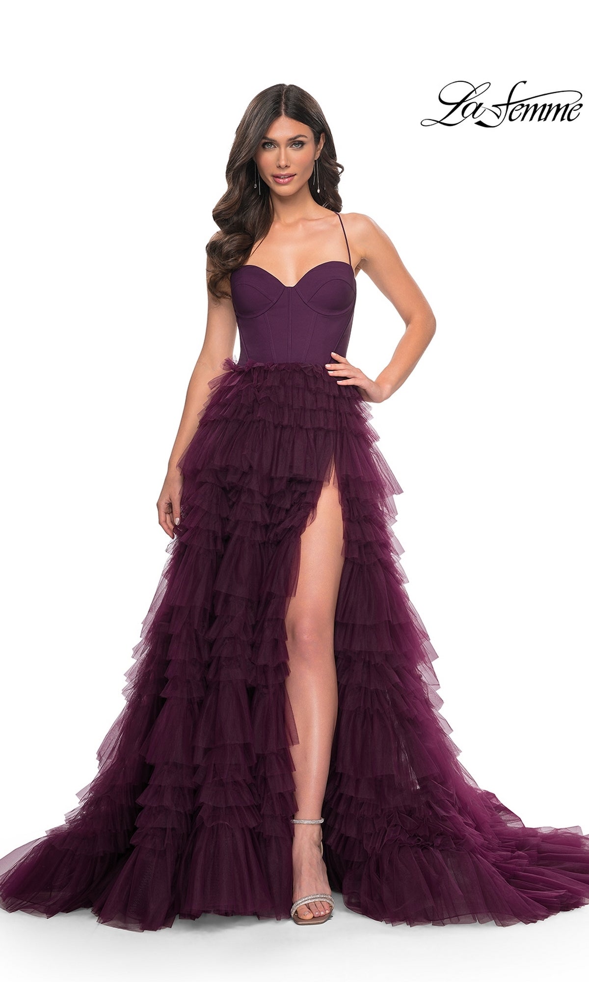 A woman poses against a white background wearing the Lace-Up Ruffle Long Prom Ball Gown: La Femme 32071, a deep purple strapless gown with a sweetheart corset bodice, ruffled tulle skirt, and high slit. The La Femme logo appears in the top right corner.